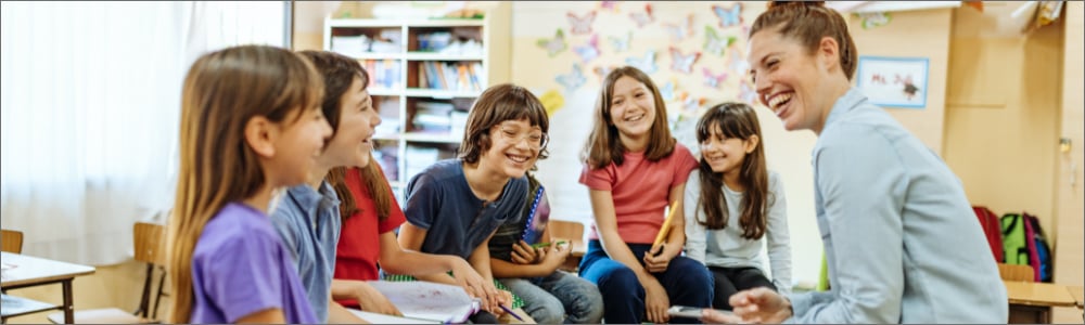 Teacher with group of middle school students laughing together in a group in a classroom setting